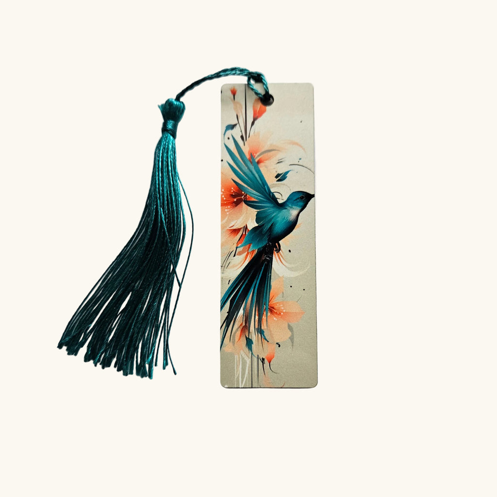 A rectangular wooden bookmark featuring a painted blue bird and coral floral design, with a dark teal tassel attached at the top, photographed on a light gray background.