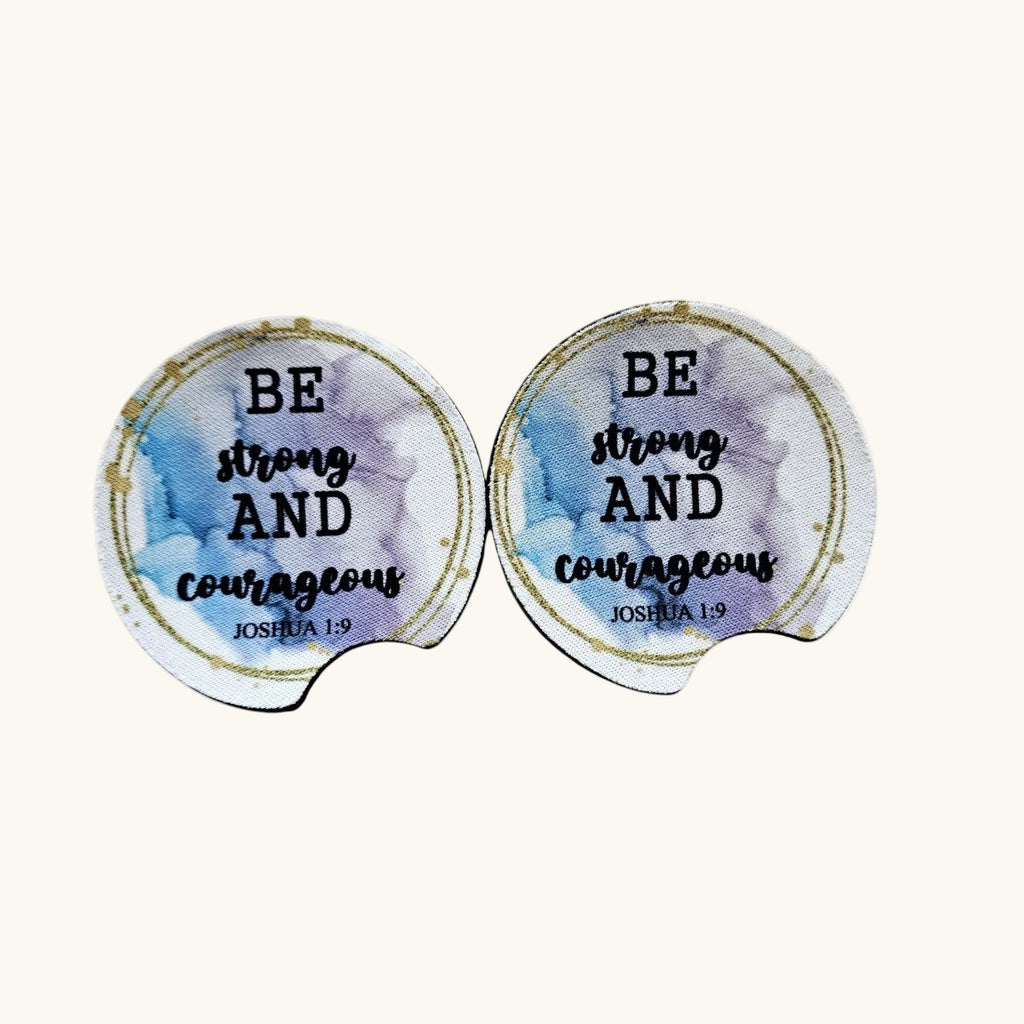 Two round mouse pads with a watercolor design in blue, purple, and white, featuring the text 'BE strong AND courageous JOSHUA 1:9' in black lettering with a gold circular border, set against a light beige background.