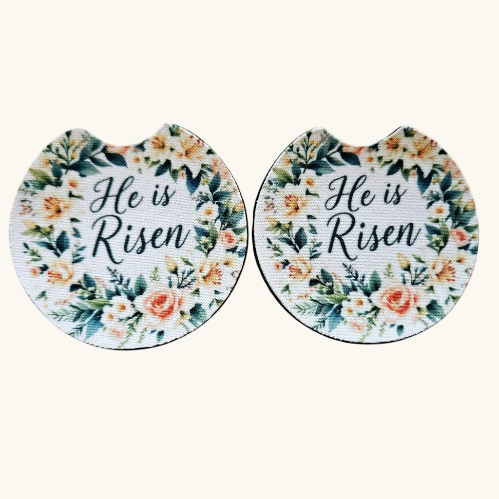Two oval-shaped mouse pads with a floral design and the text 'He is Risen' in black script, displayed side-by-side on a light cream background.